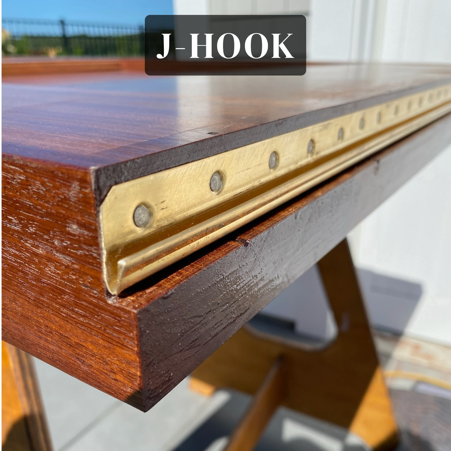 Solid-bronze interlocking threshold hook strip, also called a J-hook, fastened to the bottom of a wood door